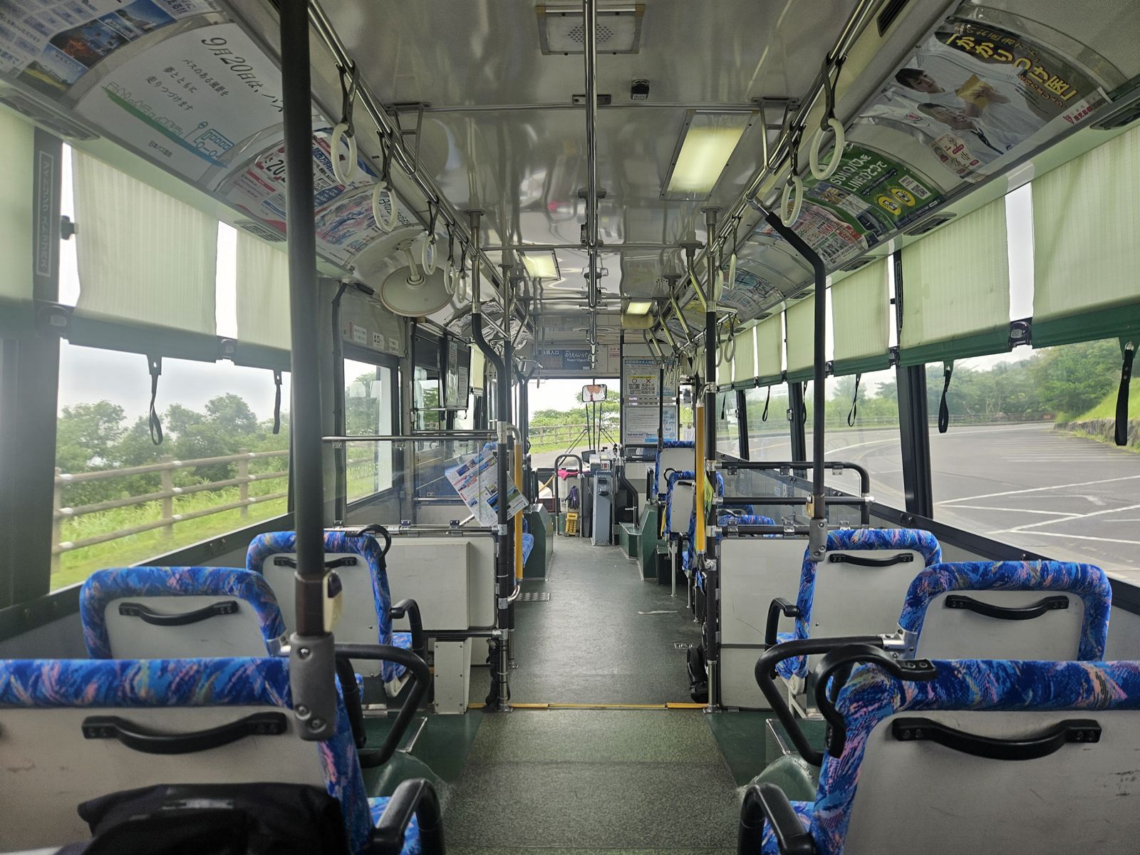 Intérieur d'un bus japonais vide, avec des sièges bleus et des publicités accrochées au plafond.