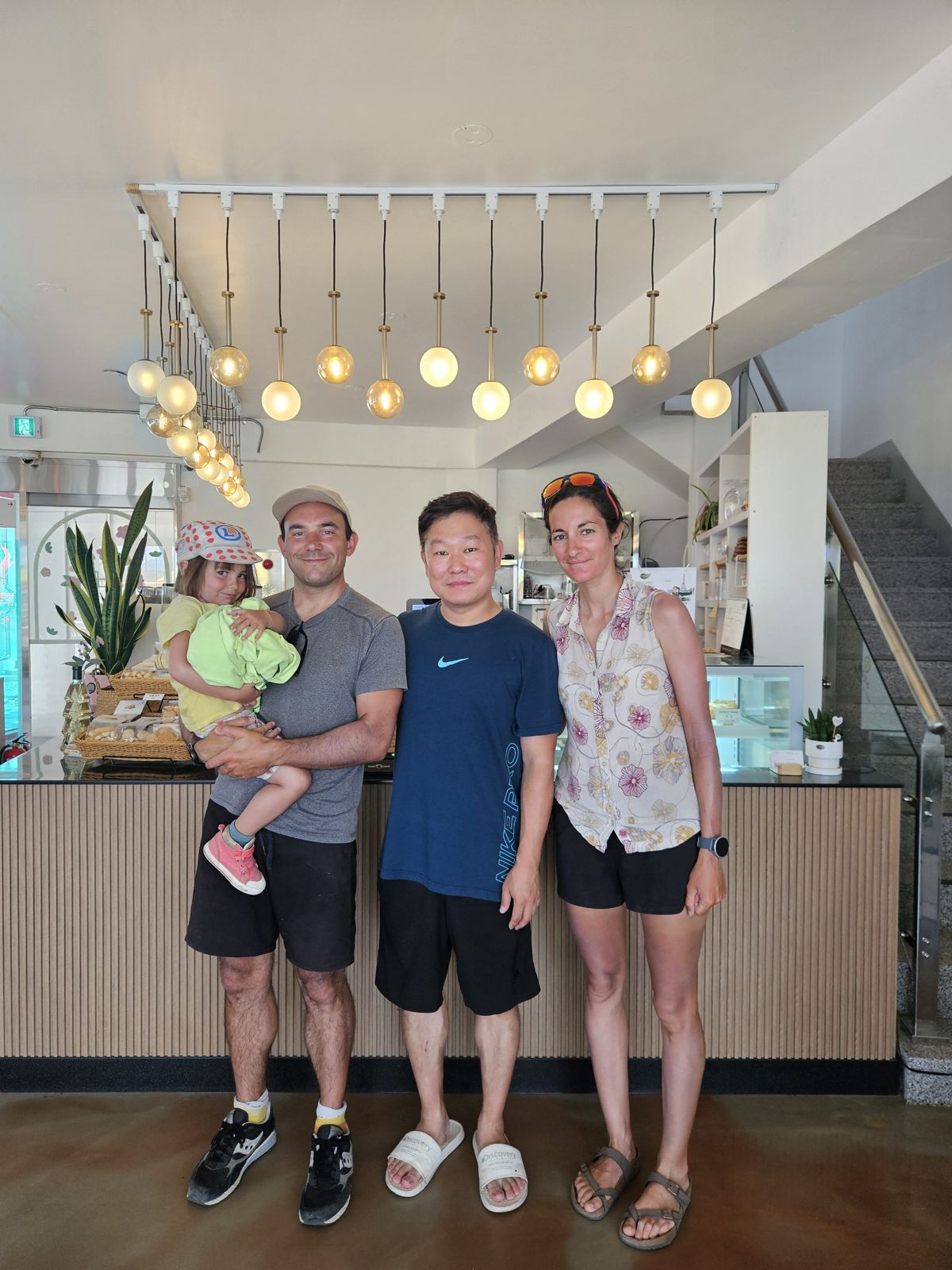 Quatre personnes souriantes posent ensemble dans un café, avec une pièce lumineuse et moderne en arrière-plan.