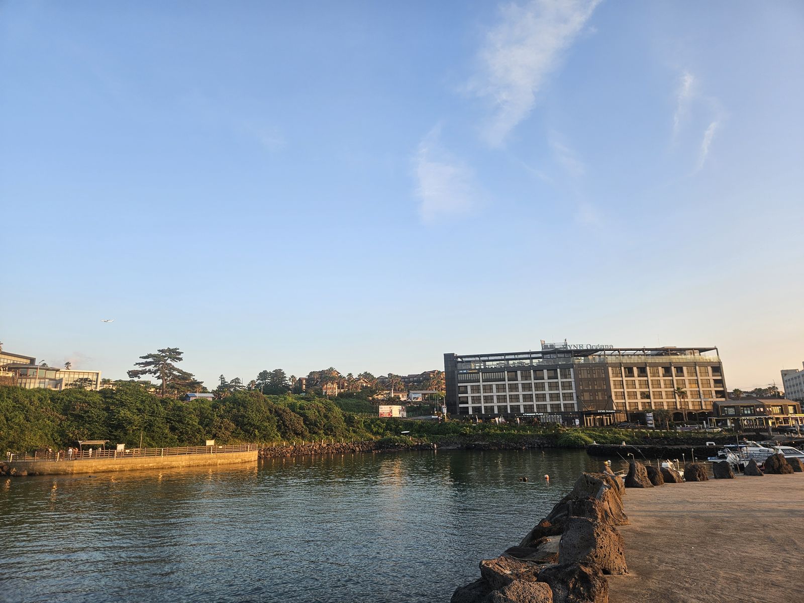 Vue du port avec un bâtiment moderne à côté de l'eau, sous un ciel clair et ensoleillé.