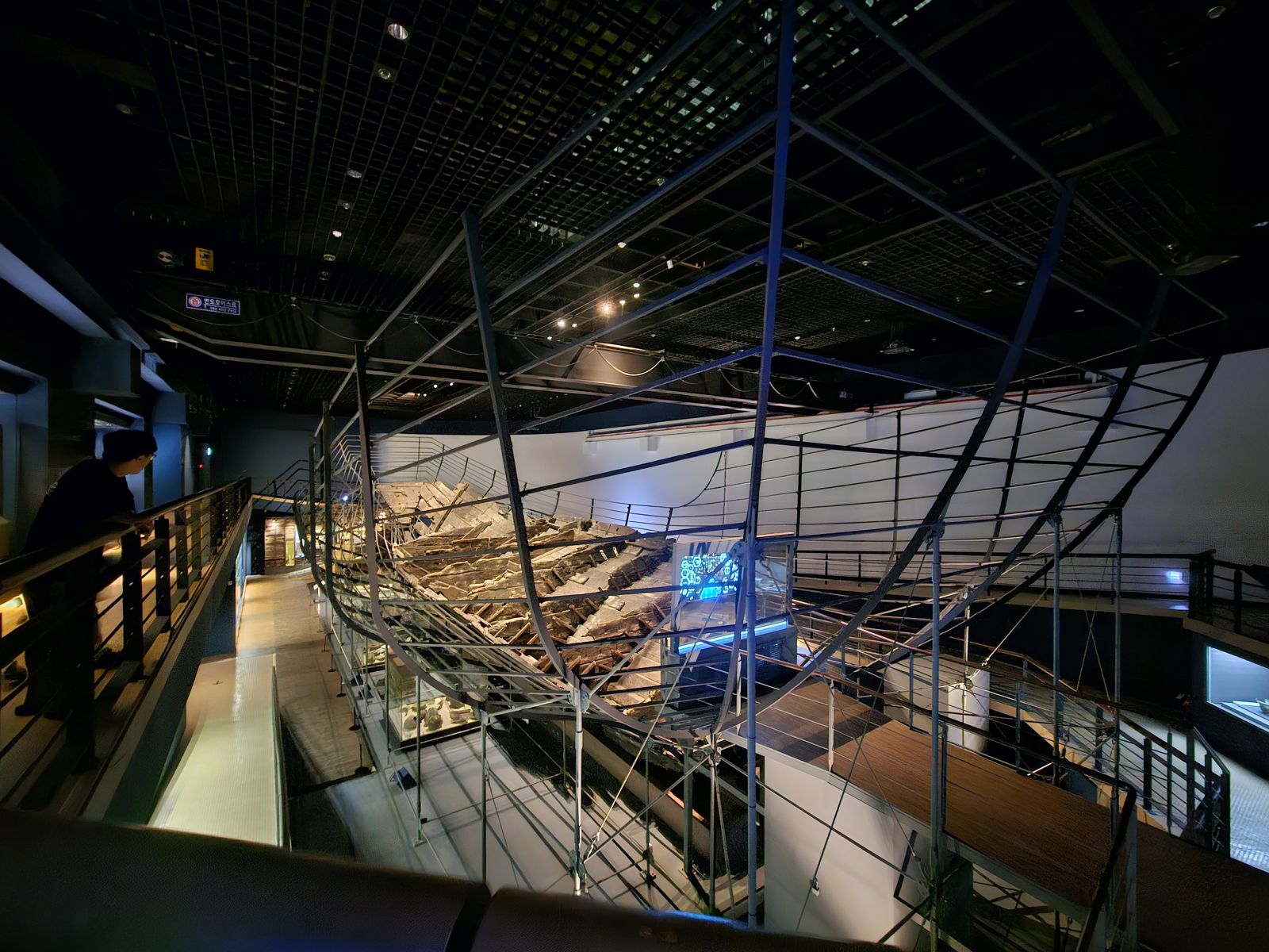 Vue intérieure du musée maritime de Mokpo, avec une reconstruction d'épave exposée sur un support métallique, entourée de lumières et d'une ambiance moderne.