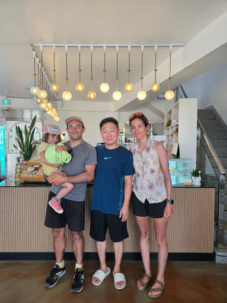 Quatre personnes souriantes posent ensemble dans un café, avec une pièce lumineuse et moderne en arrière-plan.