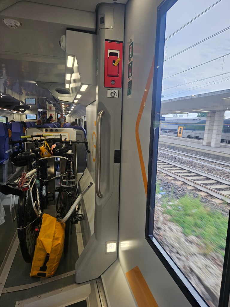 Intérieur d'un train en Italie avec des sièges vides, des vélos et des bagages à côté de la fenêtre.