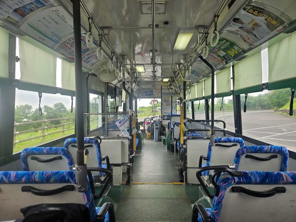 Intérieur d'un bus japonais vide, avec des sièges bleus et des publicités accrochées au plafond.