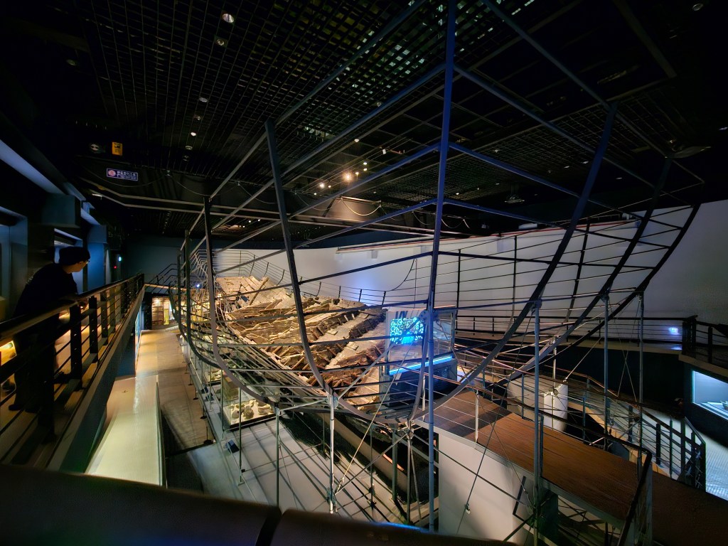 Vue intérieure du musée maritime de Mokpo, avec une reconstruction d'épave exposée sur un support métallique, entourée de lumières et d'une ambiance moderne.